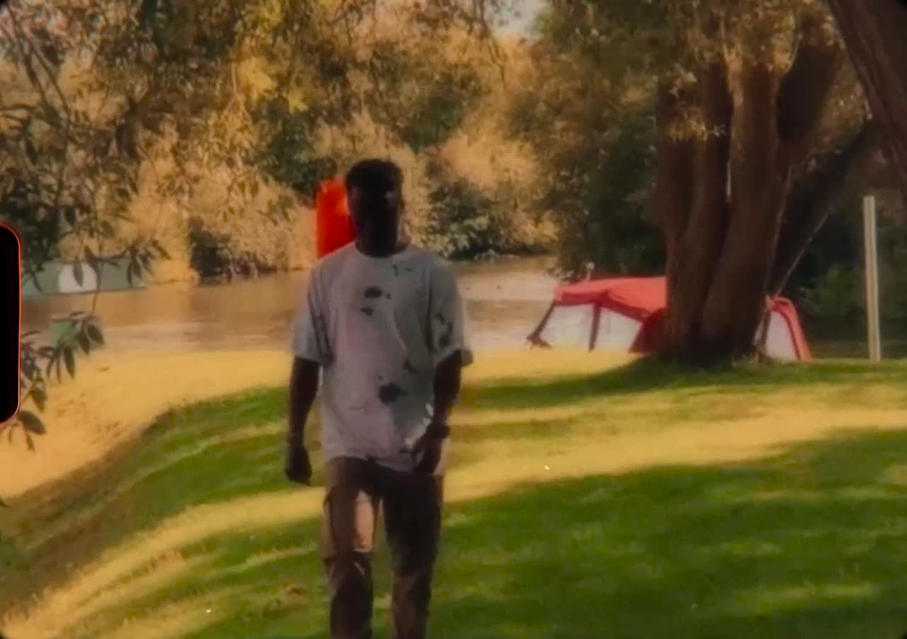 IkeN walking across a sunlit lawn by a river